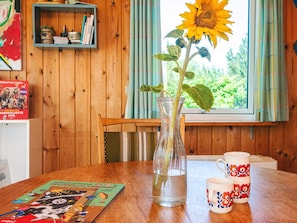 A wooden table with a clear glass vase containing a sunflower, a book, and two patterned mugs. - 5 Person Holiday Home in Knebel (Knebel)