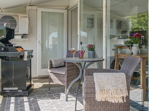An outdoor patio with a grill, wicker furniture, and a table with drinks. - 4 Star Holiday Home in Ringkobing (Ringkobing)