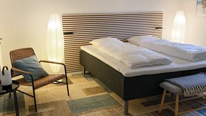 Ein Schlafzimmer mit einem Bett, einem Sessel, einem Nachttisch und einer Wandlampe.