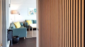 Een moderne woonkamer met een blauwe bank, een bijzettafeltje en een zwarte pot op de vloer.