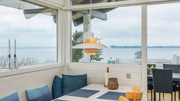 Een eetruimte met een tafel en stoelen, een hanglamp en uitzicht op het water.