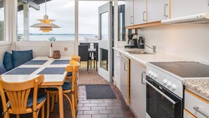 Een moderne keuken met een groot raam, een eethoek met houten stoelen en uitzicht op het water.