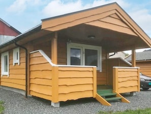 Uma casa de madeira térrea com varanda, porta frontal e um pequeno lance de escadas que dá acesso à entrada.