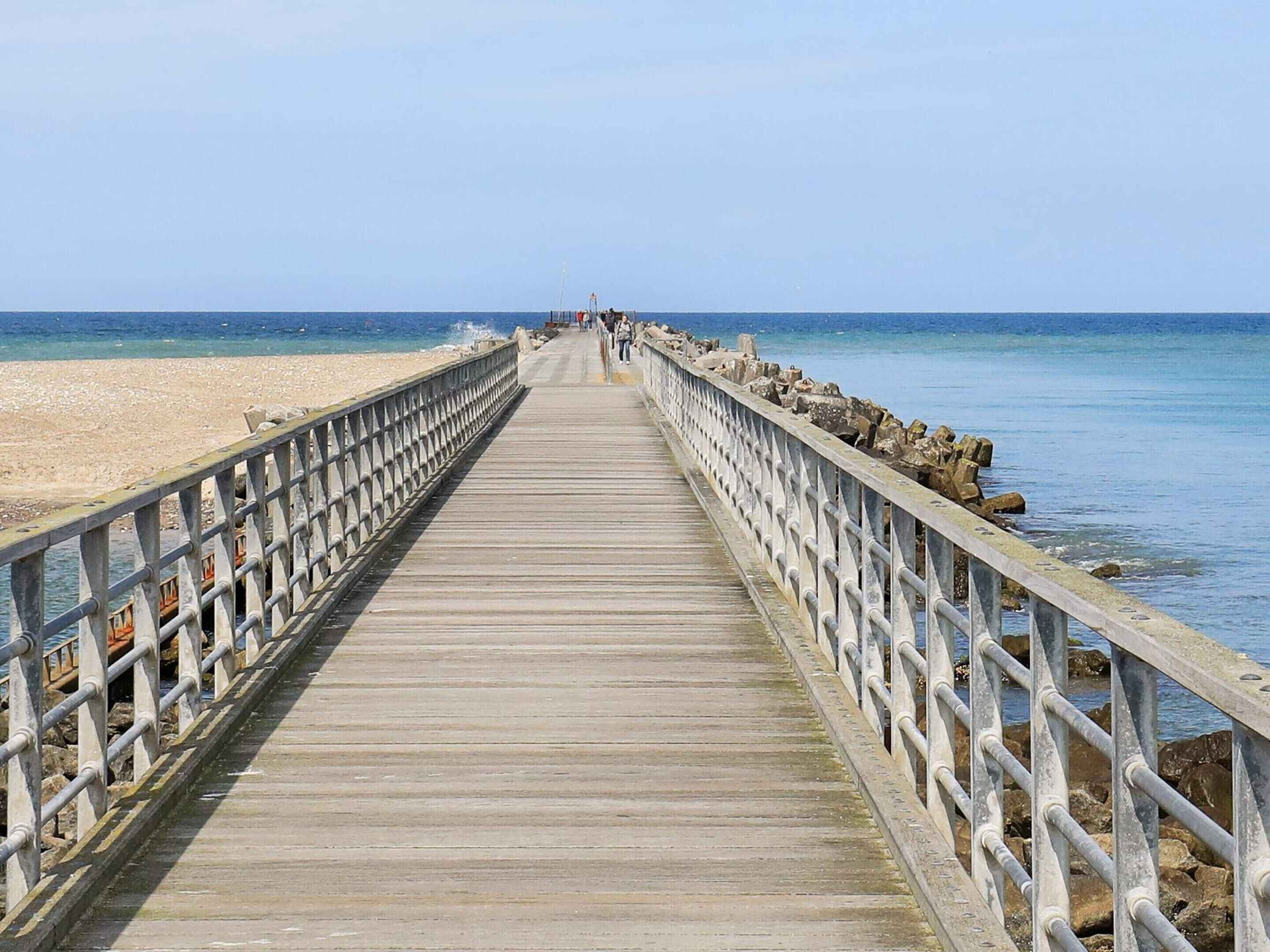 A wooden pier extending into the sea with railings on both sides.
