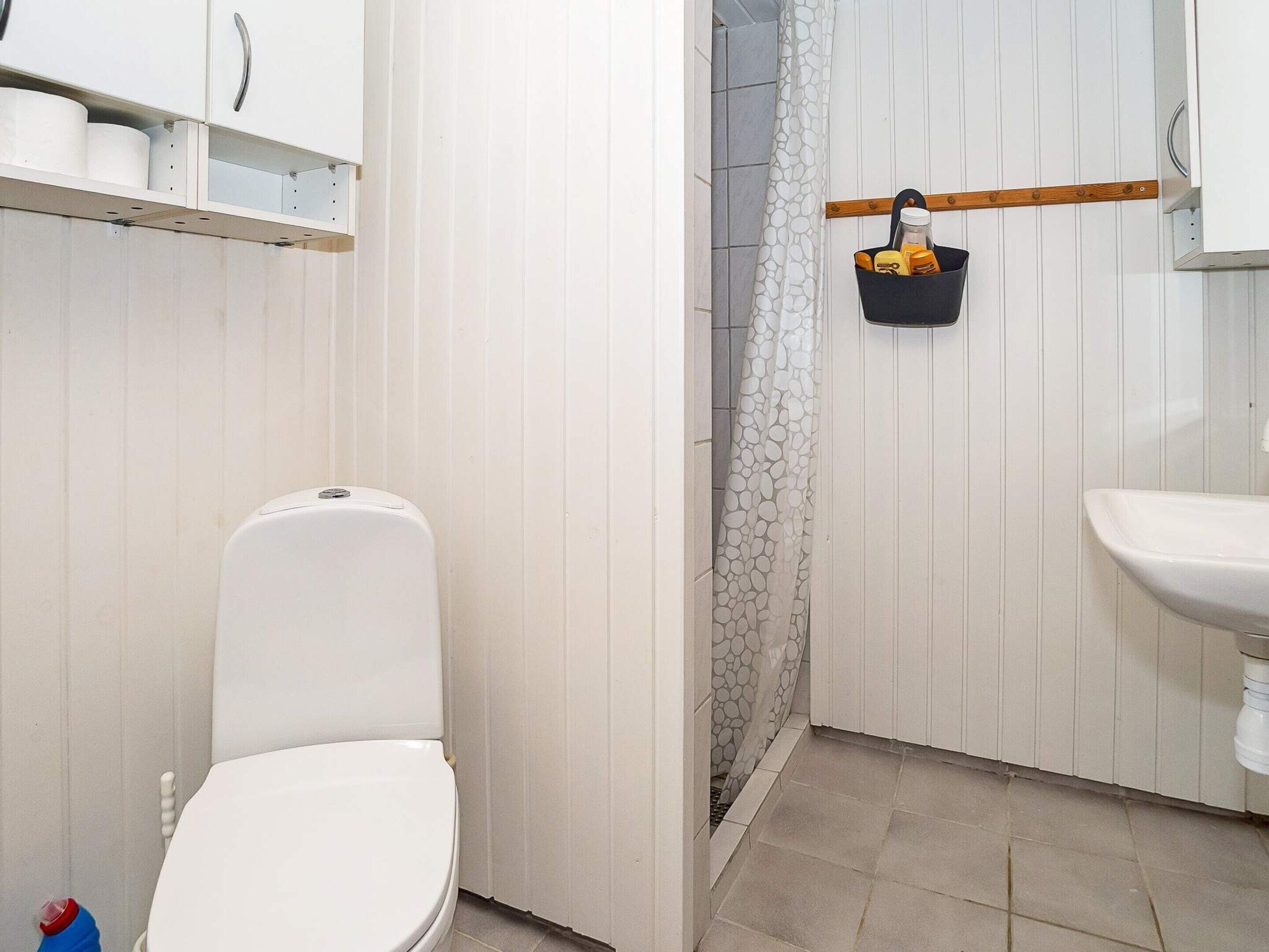 A bathroom with a toilet, a sink, and a shower area.