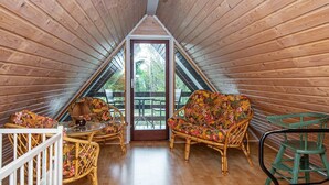 A cozy attic room with wooden walls, a wooden floor, a colorful sofa, a small table, and a green chair. - 6 Person Holiday Home in Skjern (Skjern)