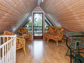 A cozy attic room with wooden walls, a wooden floor, a colorful sofa, a small table, and a green chair. - 6 Person Holiday Home in Skjern (Skjern)