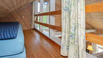 Quarto com teto de madeira, uma cama beliche, janela com cortinas e luminária suspensa.