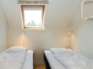 Ein kleines, sauberes Zimmer mit zwei Einzelbetten, einem Oberlicht und einer Wand-Klimaanlage.