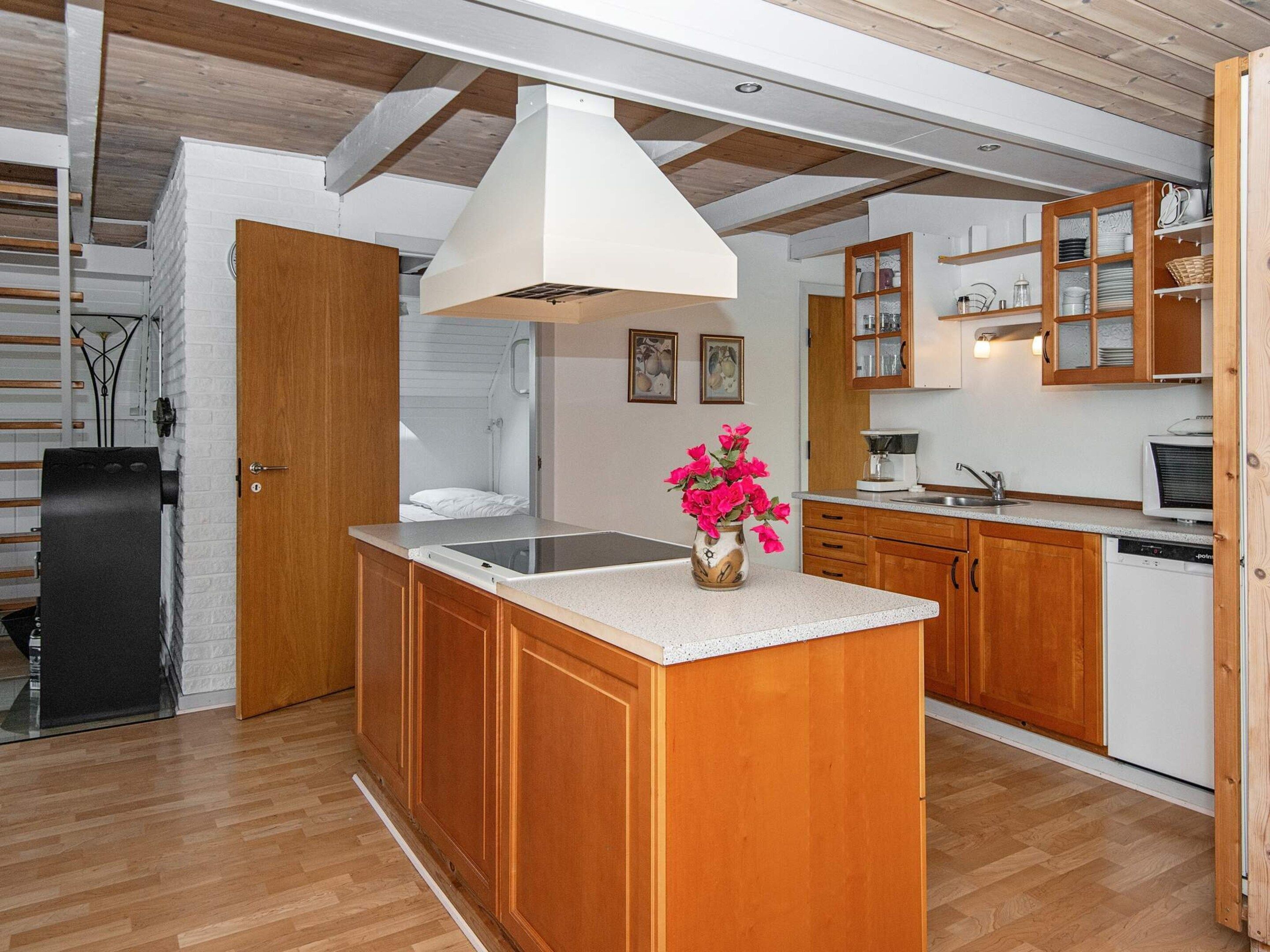 Una cocina moderna con armarios de madera, una isla central y encimera blanca.
