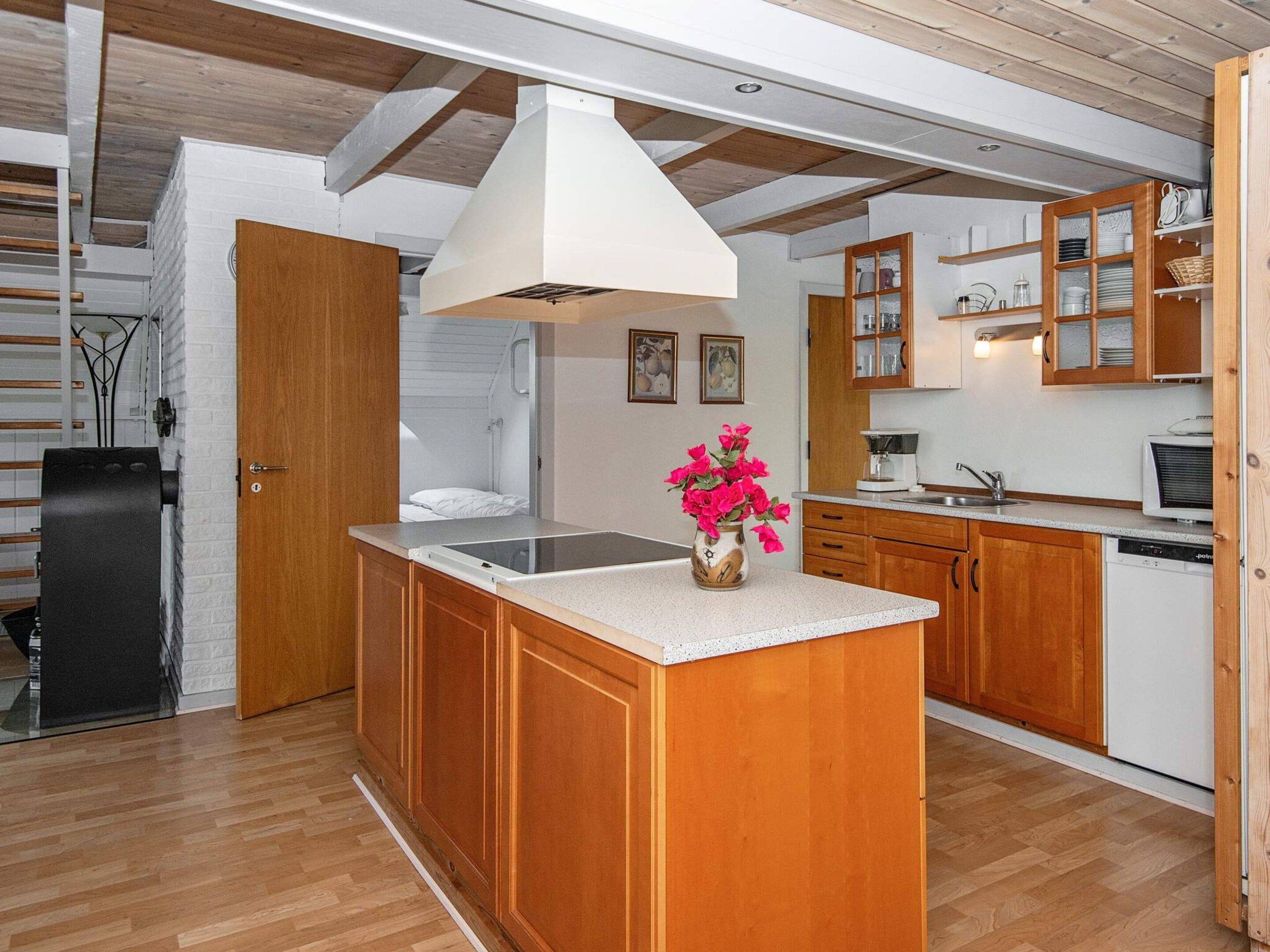 Una cocina moderna con armarios de madera, una isla central y encimera blanca.