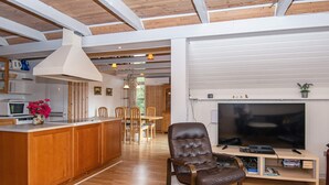 A spacious living area with a wooden floor, a large TV, and a leather chair. - 6 Person Holiday Home in Skjern (Skjern)
