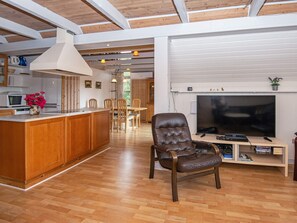 A spacious living area with a wooden floor, a large TV, and a leather chair. - 6 Person Holiday Home in Skjern (Skjern)