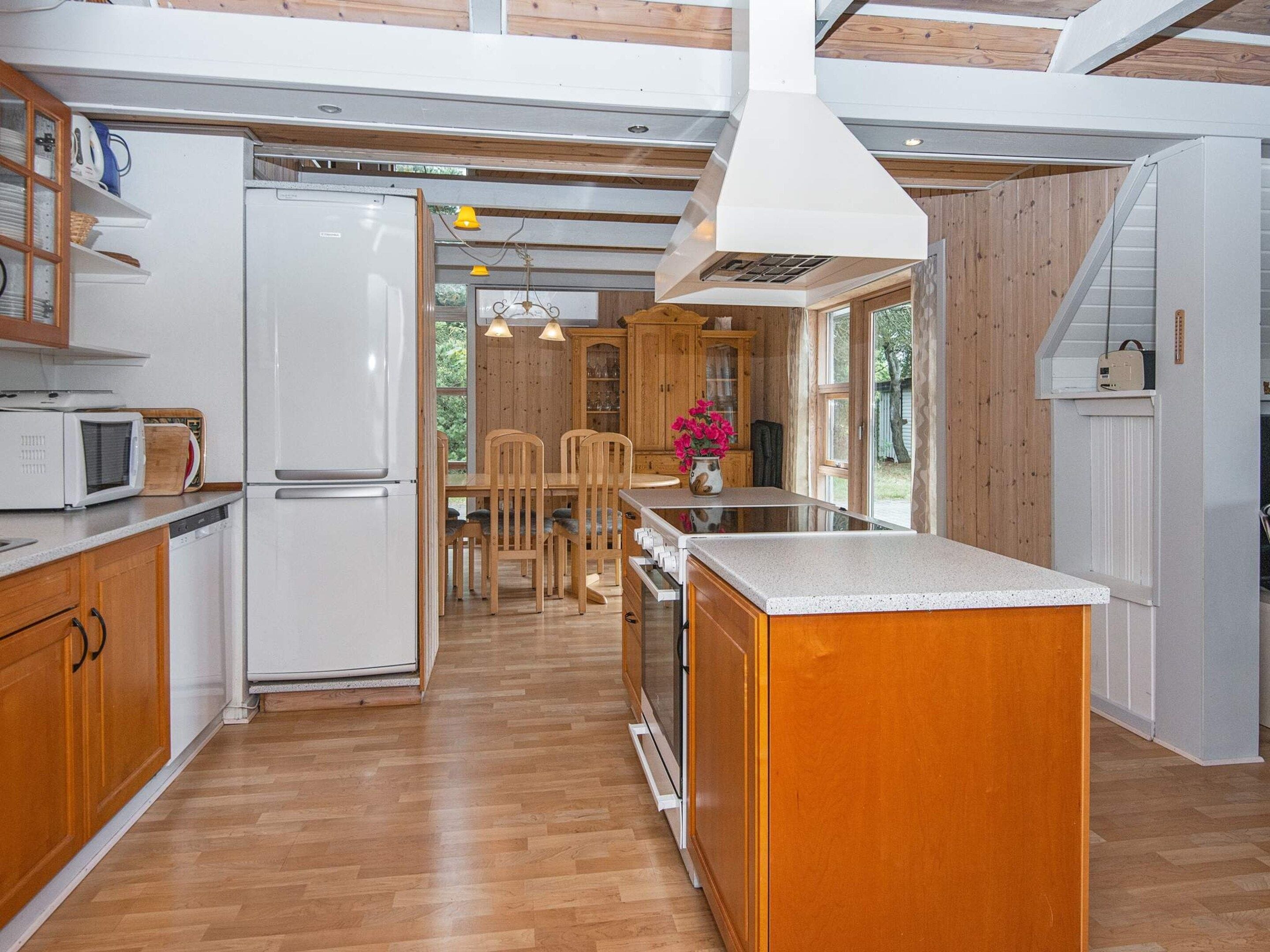A modern kitchen with wooden cabinets, a white refrigerator, and a central island.