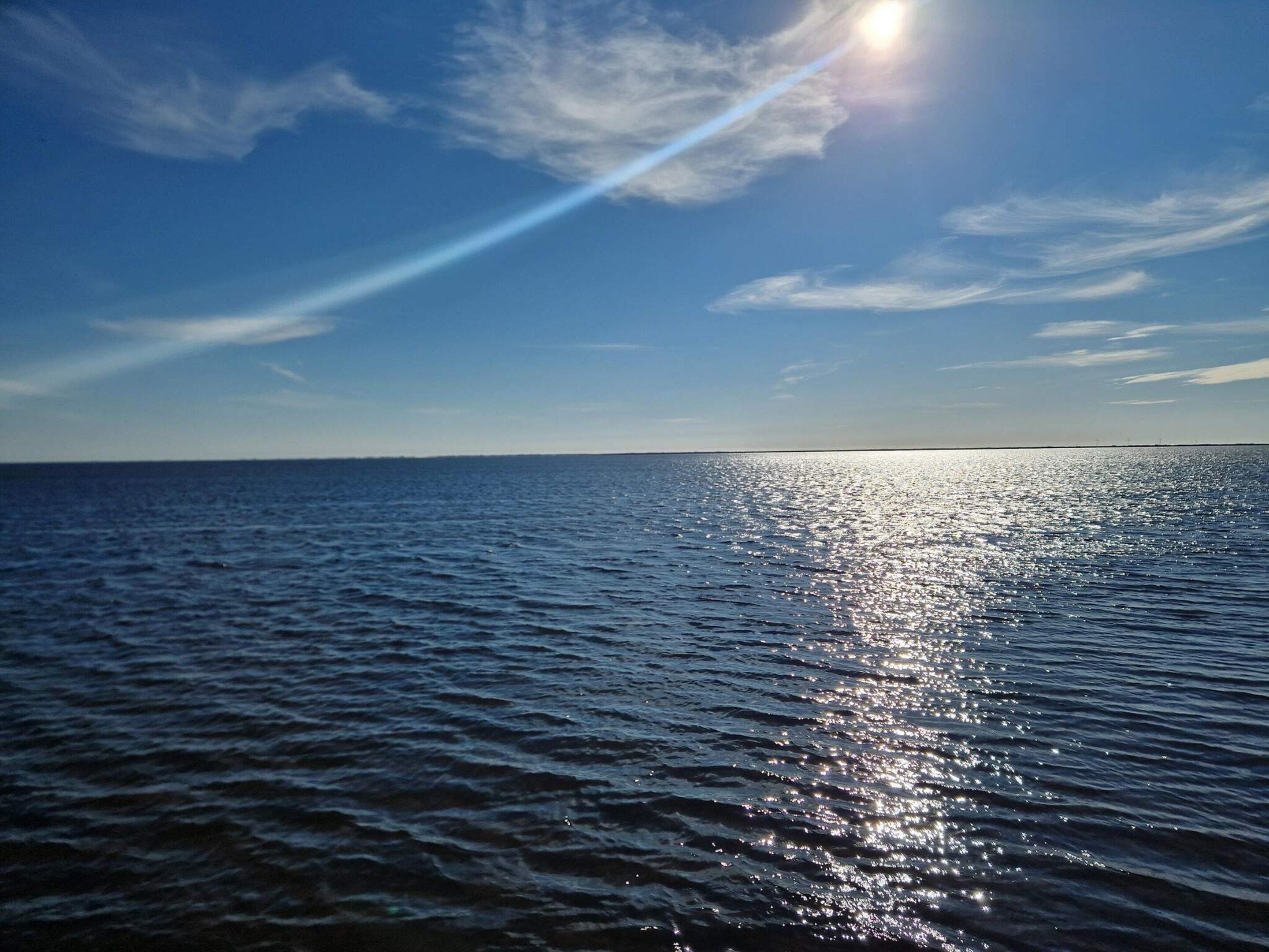 Mar tranquila con el sol reflejado en el agua.