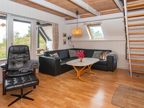 A modern living room with a leather chair, a black sofa, a round coffee table, and a wooden floor. - 6 Person Holiday Home in Skjern (Skjern)