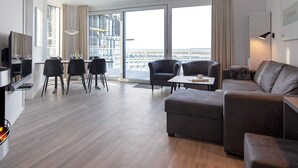 Un salon moderne comprenant un canapé, des fauteuils, une table à manger et un téléviseur.