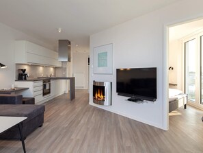 A modern living space with a kitchen, dining area, and a fireplace.