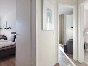 A hotel room with a bed, bedside lamps, a framed picture, and a view into the bathroom.