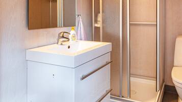 Un bagno con un lavandino bianco, uno specchio e un box doccia.