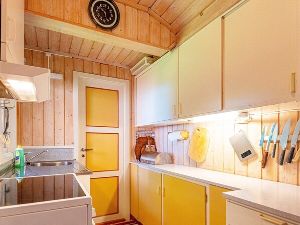 A kitchen with wooden walls, a clock, and a sink. - 6 Person Holiday Home in Sandefjord (Sandefjord)