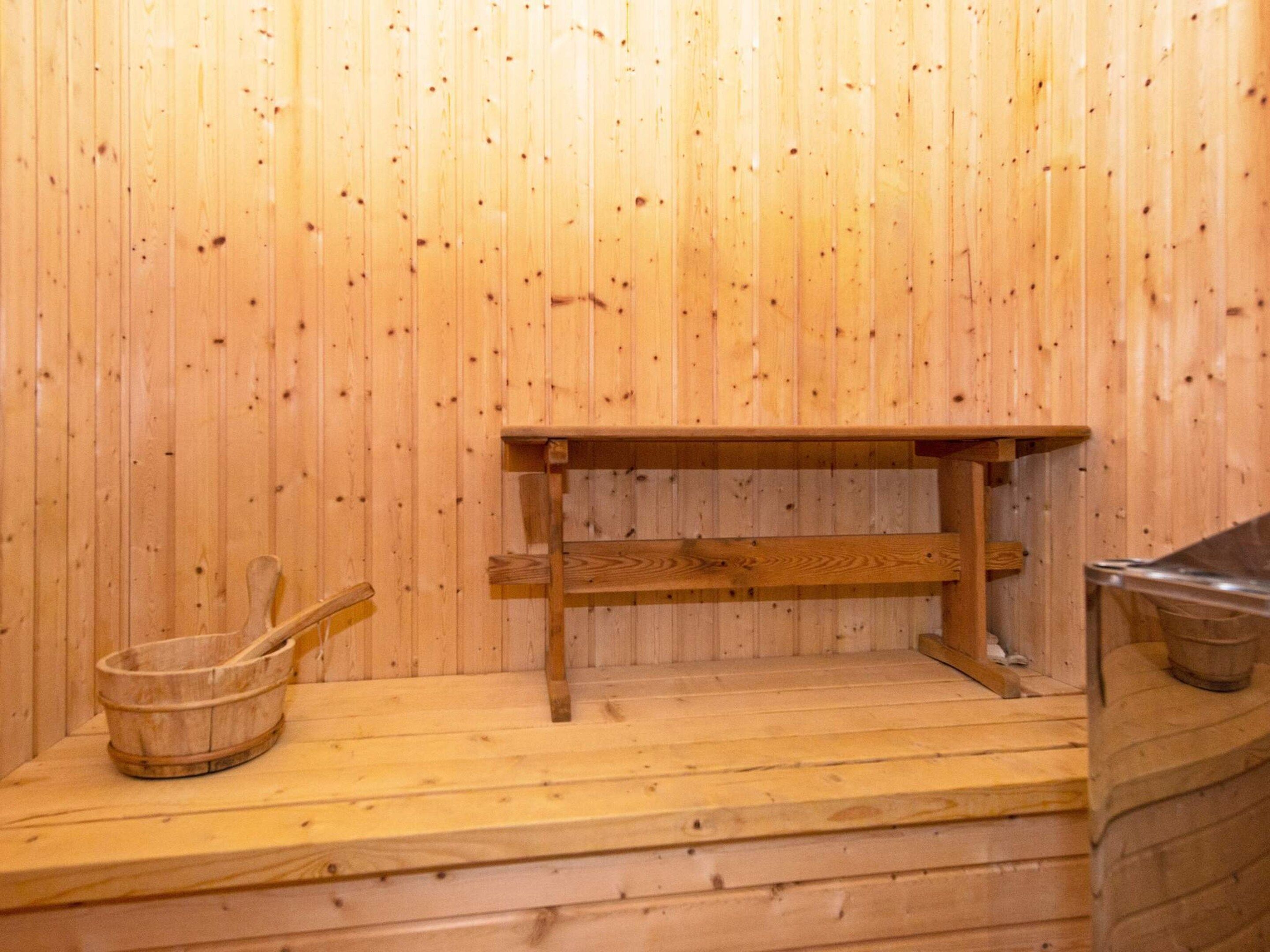 A wooden sauna room with a wooden bench and a wooden bucket.