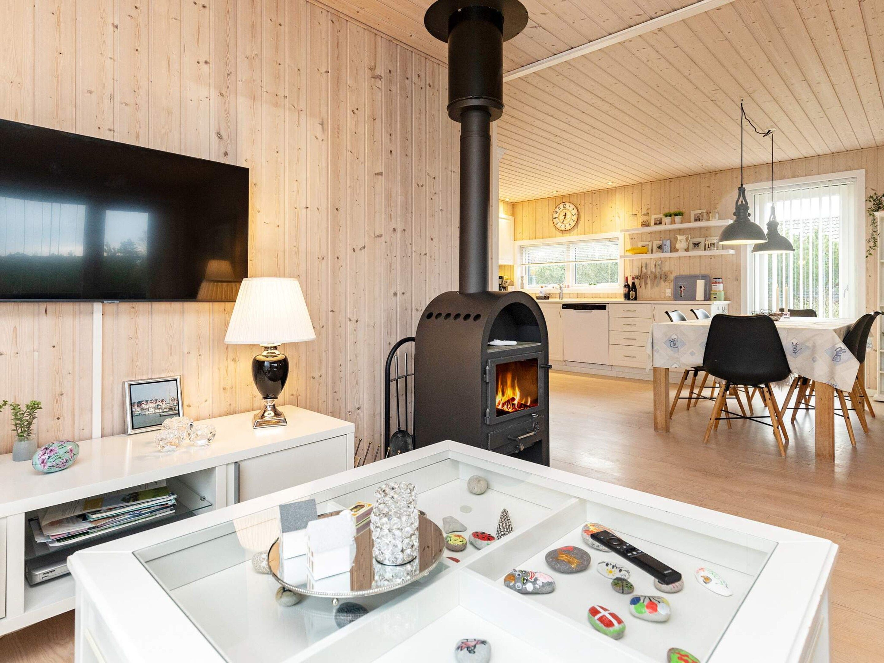 A modern kitchen with wooden walls, a black stove, and a dining area with a table and chairs.