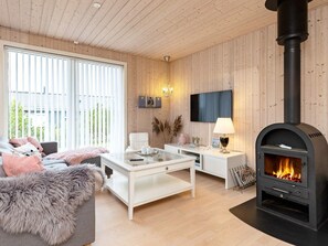 Un salon moderne avec une cheminée, des murs en bois, un canapé, une table basse et un téléviseur.