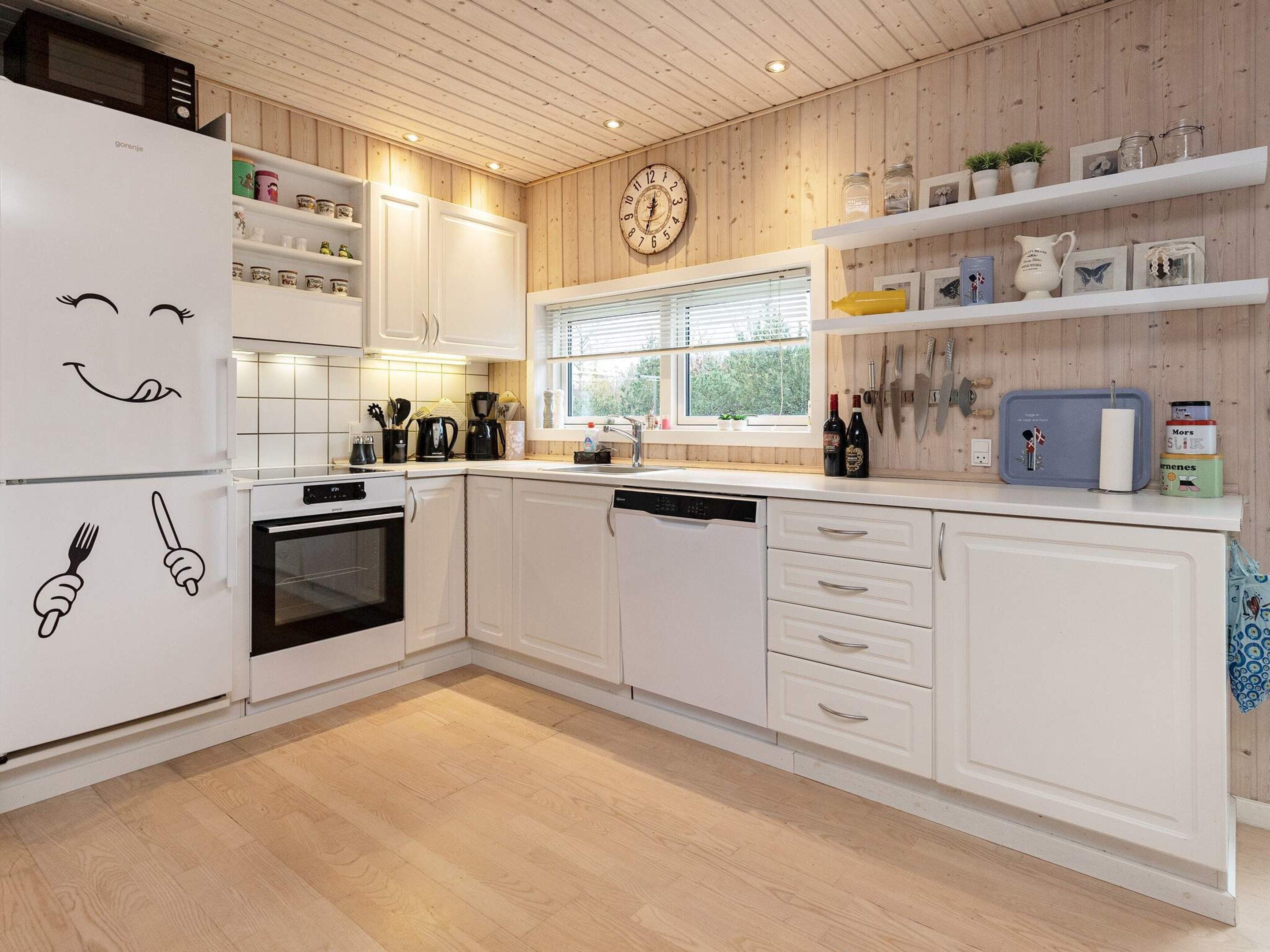 A kitchen with white cabinets, a microwave, a clock, and various kitchen appliances.
