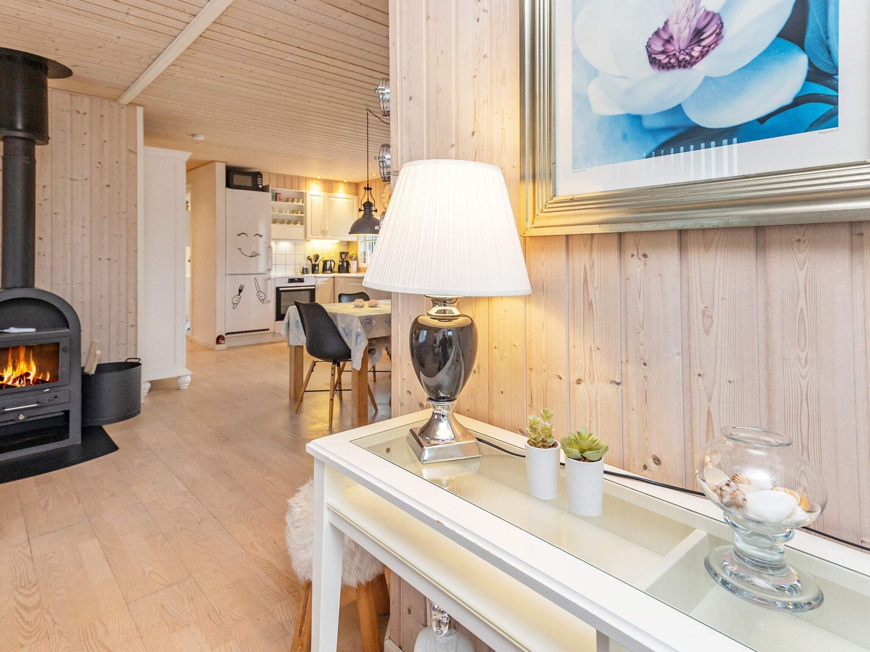 Een moderne woonkamer met een open haard, een eethoek en een keuken op de achtergrond.