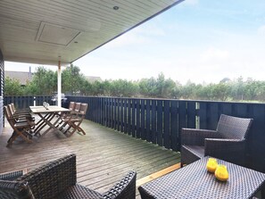 Une terrasse extérieure avec une table et des chaises, un barbecue et une vue sur les arbres et les bâtiments.