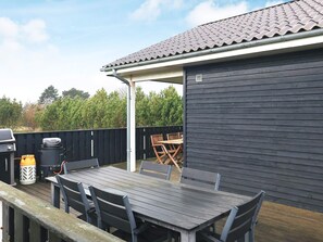 An outdoor patio with a table and chairs, a barbecue grill, and a trash bin. - 9 Person Holiday Home in Humble (Sydlangeland)