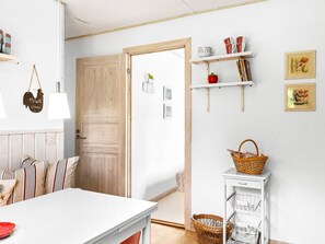 A room with a white table, striped cushions, a wooden door, and a white cabinet with baskets. - 8 Person Holiday Home in Skanes Fagerhult (Skånes Fagerhult)