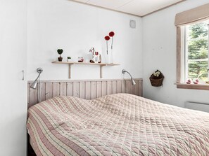 A bedroom with a bed, bedside lamps, a window with a view, and a shelf with decorative items. - 8 Person Holiday Home in Skanes Fagerhult (Skånes Fagerhult)