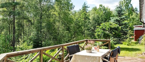 Una terraza de madera con una mesa y sillas, rodeada de un bosque.