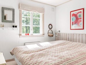 A bedroom with a large bed, a window with curtains, a bedside lamp, a wall-mounted mirror, and a framed picture. - 8 Person Holiday Home in Skanes Fagerhult (Skånes Fagerhult)