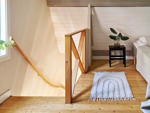 A room with a wooden staircase, a small bedside table with a plant, a white bed, and a grey rug. - 6 Person Holiday Home in Kopingsvik (Kopingsvik)