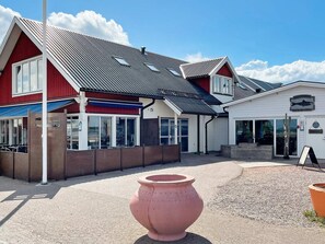 A building with a red facade, a metal roof, and a sign indicating a restaurant. - 6 Person Holiday Home in Kopingsvik (Kopingsvik)