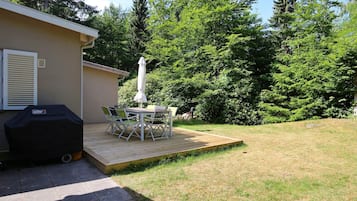 A patio with a table and chairs, a grill, and a covered umbrella.