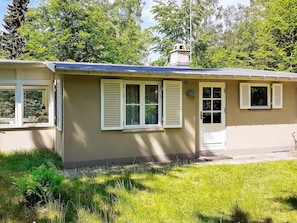 A single-story building with a flat roof, a chimney, and multiple windows with shutters. - 4 Person Holiday Home in Frederiksvaerk (Frederiksvaerk)