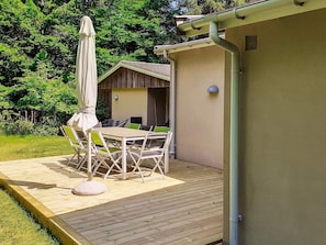 An outdoor patio with a table and chairs, a covered umbrella, and a wooden deck. - 4 Person Holiday Home in Frederiksvaerk (Frederiksvaerk)