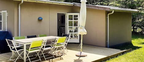 A patio with a table and chairs, a covered umbrella, and a door leading to a covered area.
