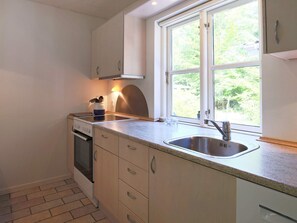 Una cocina con ventana, un lavabo, armarios y una estufa.