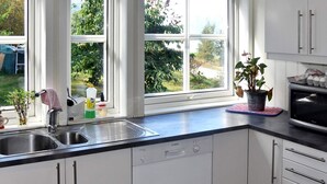 A kitchen with white cabinets, a Bosch dishwasher, a sink, and a window with a view of greenery. - 4 Star Holiday Home in Sandane (Gloppen)