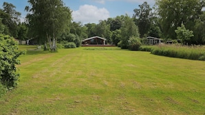 A grassy field with a wooden cabin and a smaller structure in the background. - 4 Star Holiday Home in Jaegerspris (Jægerspris)
