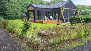 A modern house with a large deck, outdoor seating, and a swing set. - 6 Person Holiday Home in Juelsminde-by Traum (Horsens)