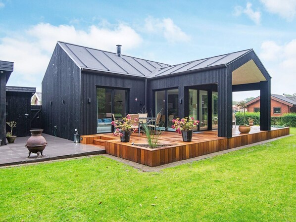 A modern house with a large deck, a patio, and a garden.