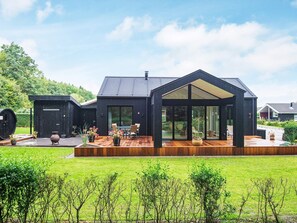 A modern house with a large deck, a conservatory, and a garage.