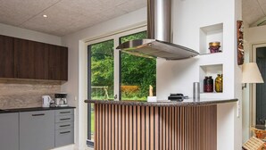 A modern kitchen with a central island, grey cabinets, and a view of greenery outside. - 6 Person Holiday Home in Juelsminde-by Traum (Horsens)
