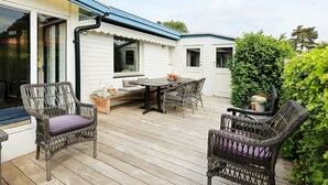 A covered outdoor patio with a dining table and chairs, surrounded by white walls and a wooden deck. - 6 Person Holiday Home in Karrebaeksminde (Karrebæksminde)